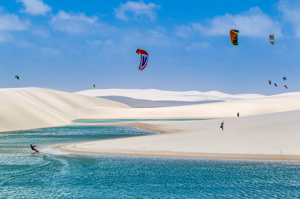 Photo avec un ciel bleu une mer bleu turquoise et des bancs de sable qui le sépare au milieu avec des kite-surfer